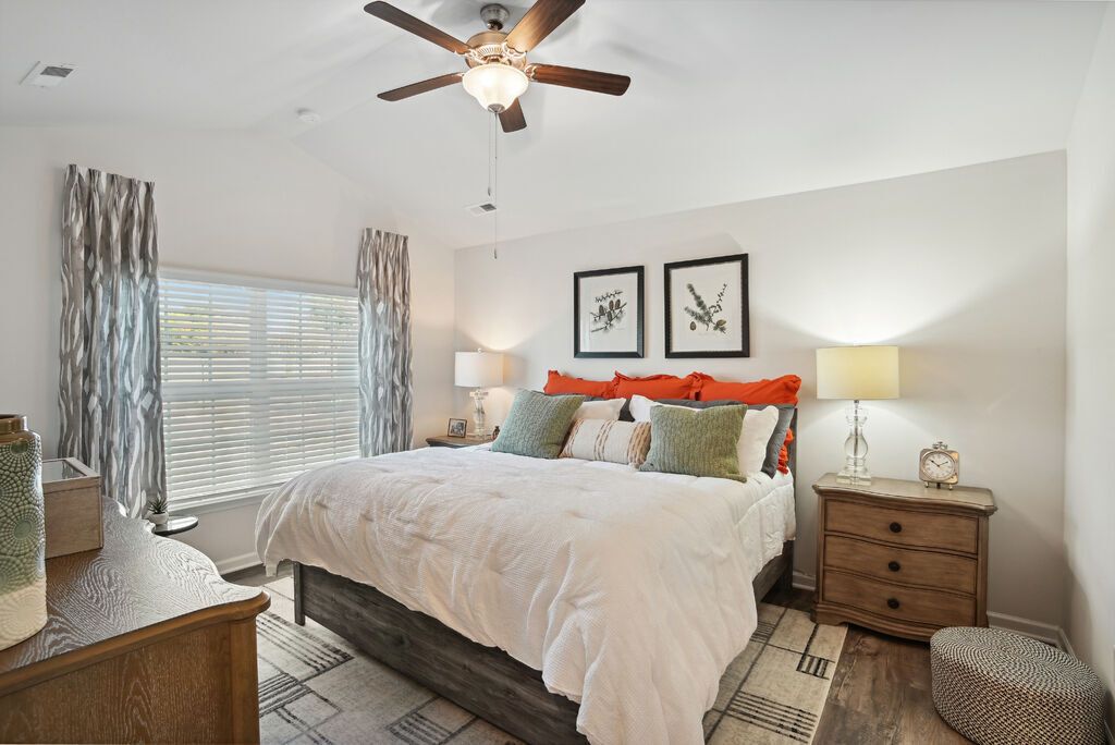 Bedroom with a large bed, two nightstands, lamps, ceiling fan, and a window with curtains.