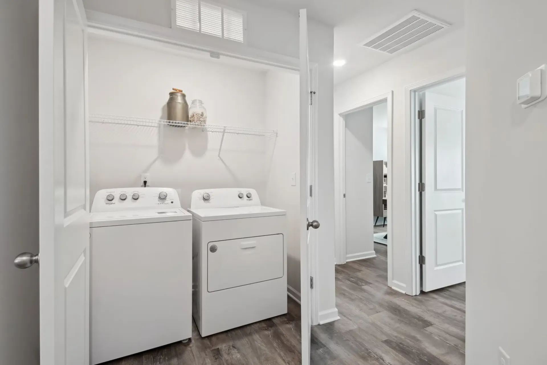 Laundry room with a washer and dryer, white shelving, and a wire shelf.