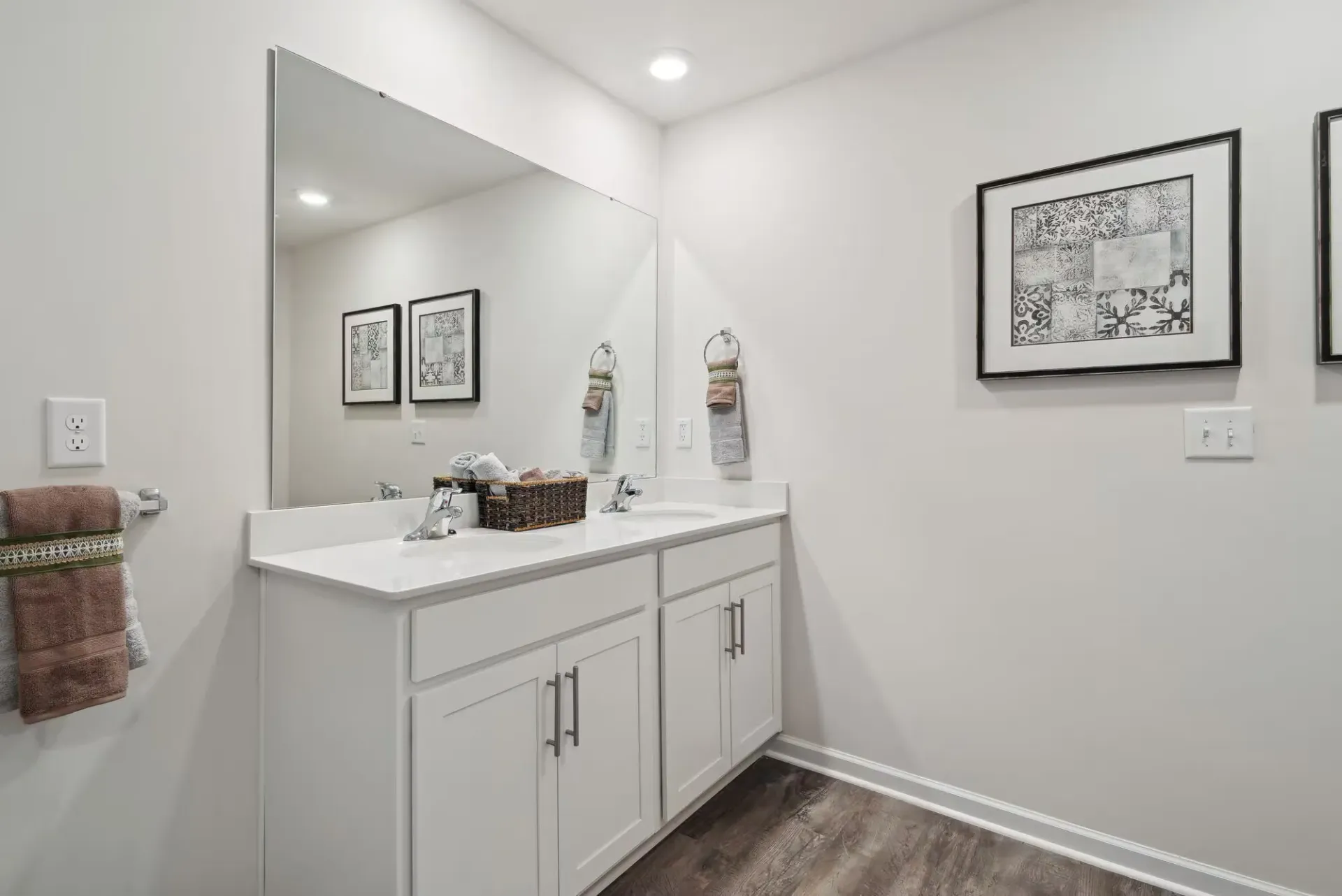 Modern bathroom with a white double-sink vanity, large mirror, and framed wall art.