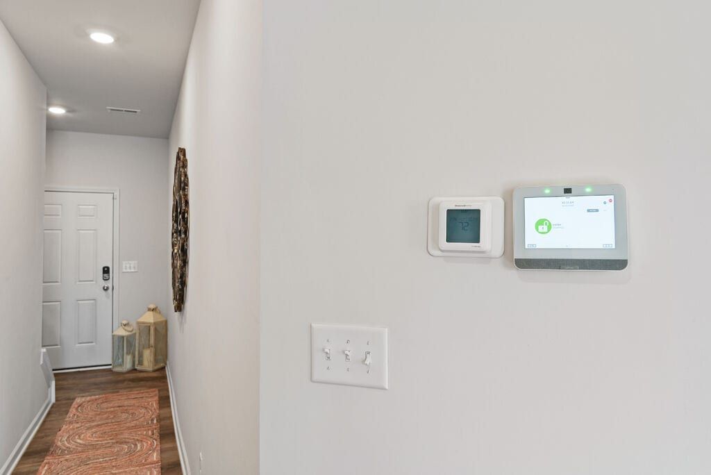 Narrow hallway with entry door at the far end, and a thermostat and control panel on the wall.