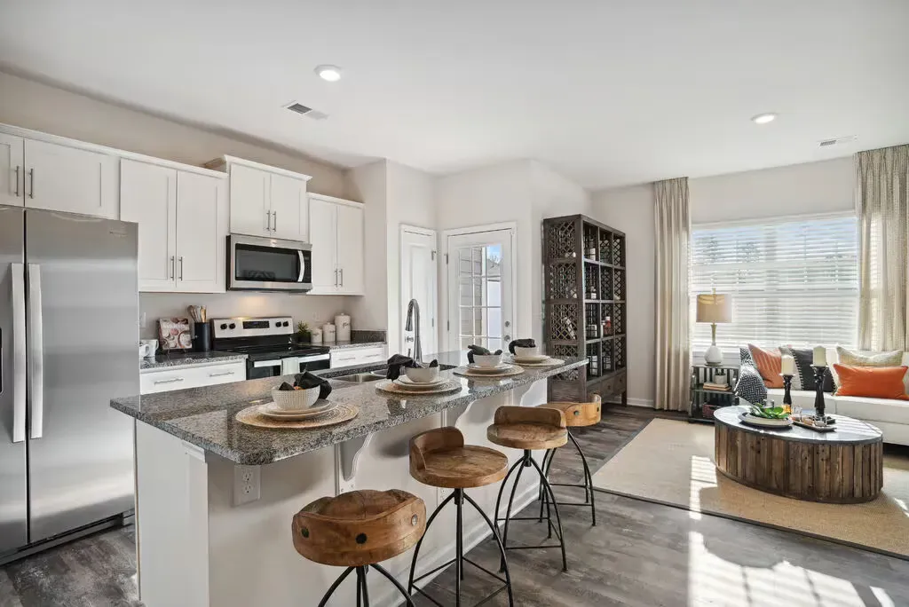 Open-concept kitchen with granite island, stainless steel appliances, and bar seating; living area visible.