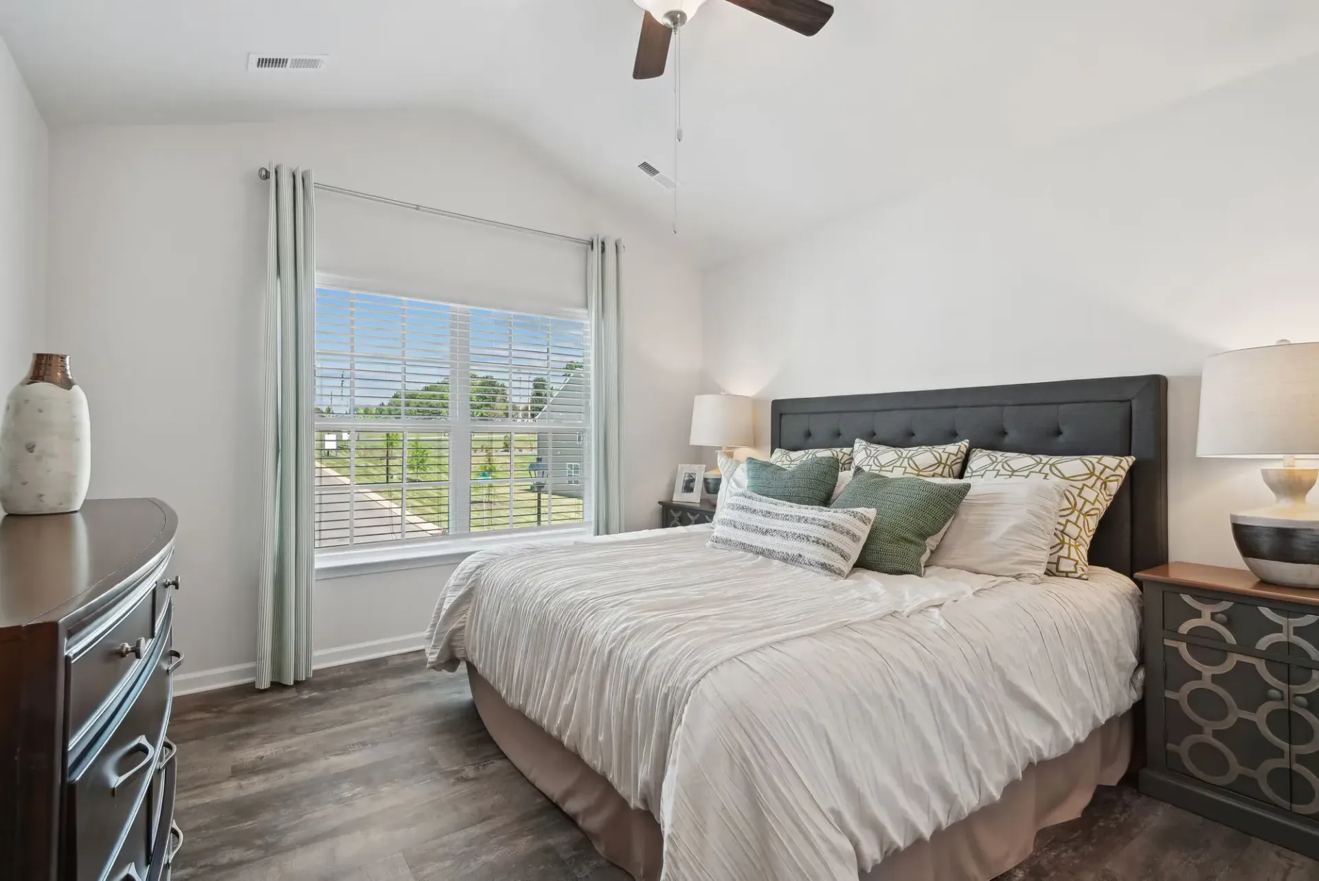 Bedroom with a large window, queen bed with tufted headboard, and matching nightstands.
