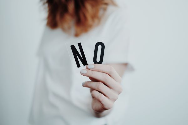 Een vrouw houdt een stuk papier vast waarop staat 'nee'.