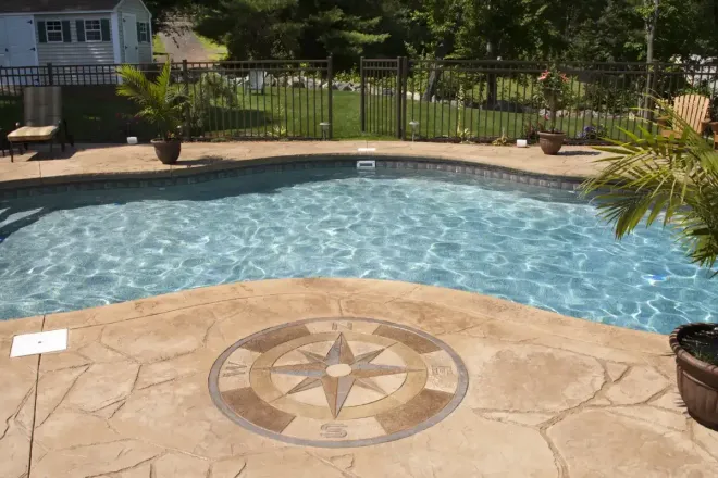Backyard pool deck with coloured concrete and custom monogram