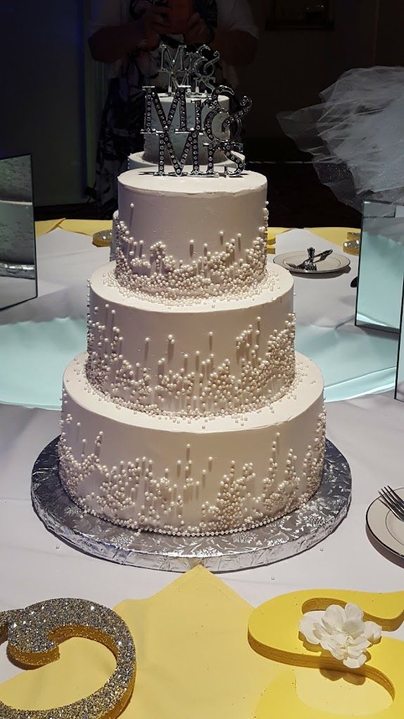 A wedding cake is sitting on a table with a bride and groom 's name on it