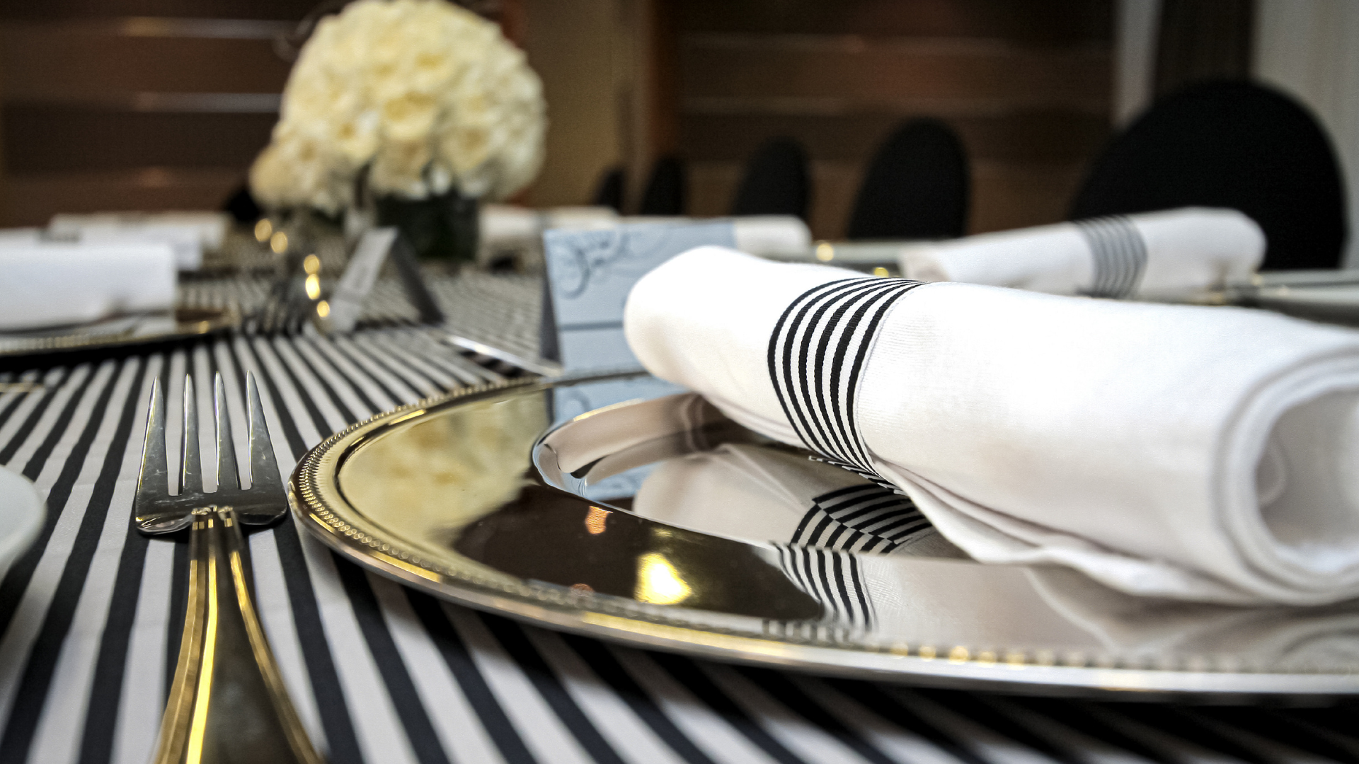 A silver plate with a napkin on it is on a striped table cloth