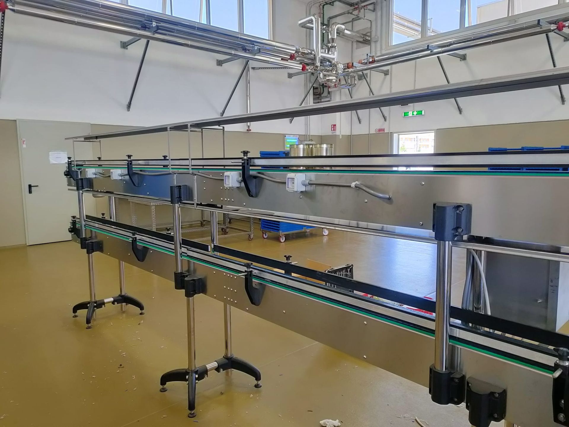 Nastri trasportatori in un ambiente di fabbrica, con nastri verdi e supporti argentati.