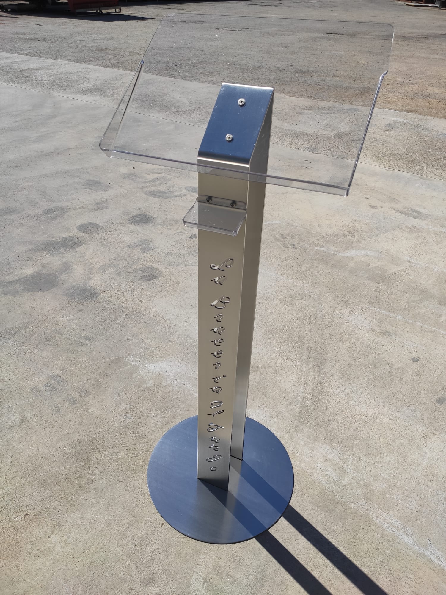 Chiosco informativo in acciaio inox con base circolare su superficie in cemento.