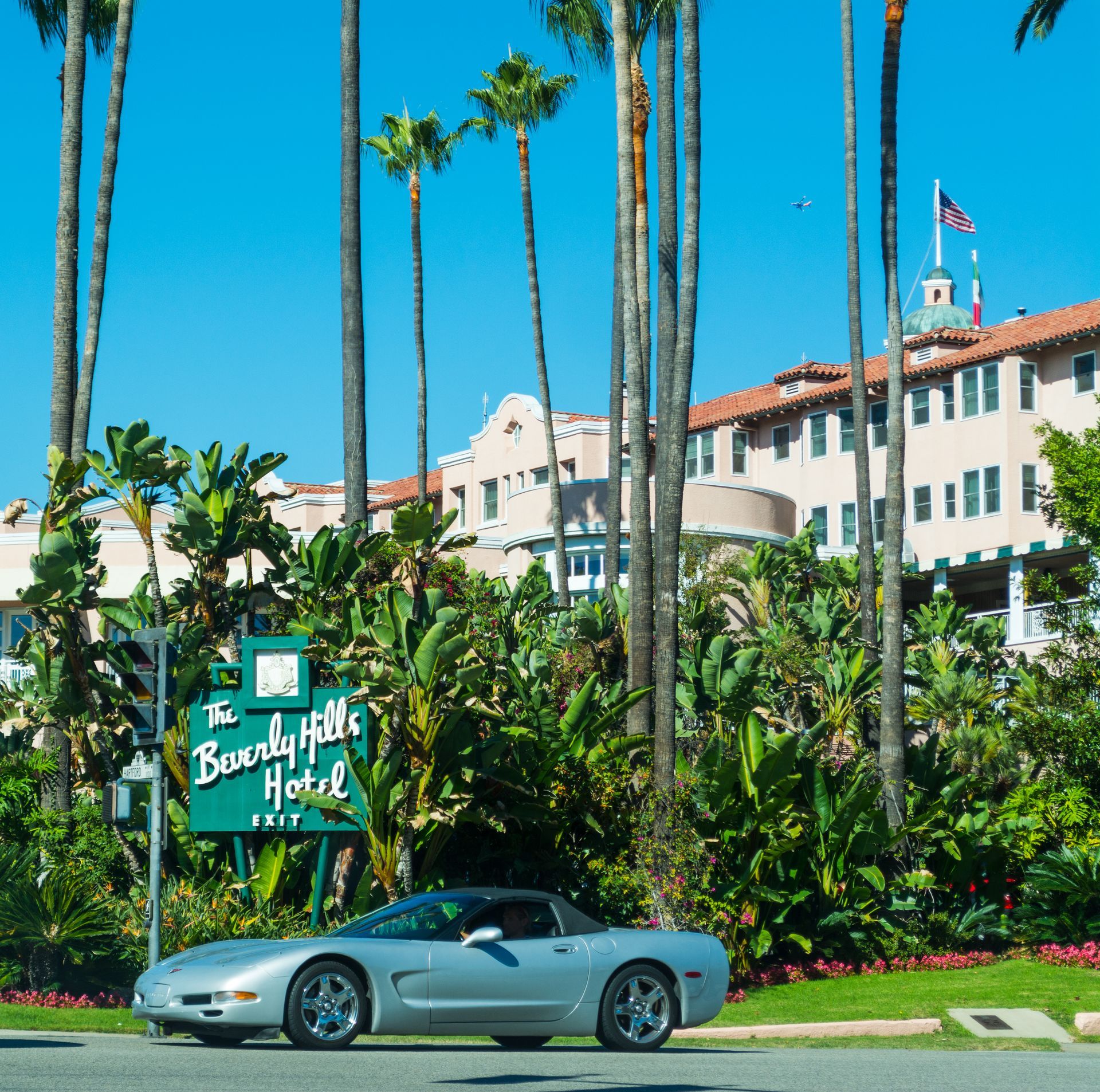 A silver sports car is parked in front of the beverly hills hotel