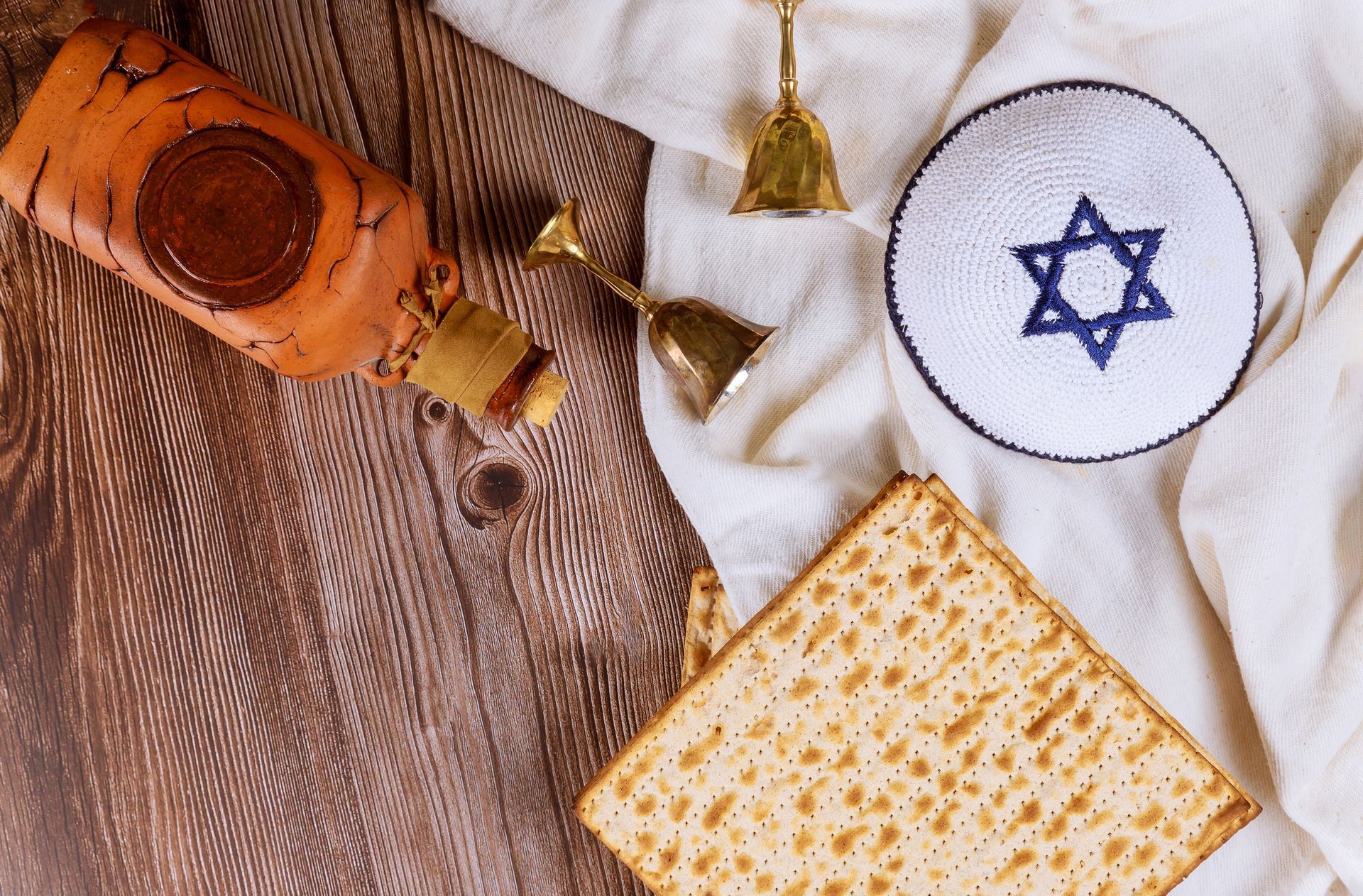 Una mesa de madera cubierta con matzá, una botella de vino, una campana y una estrella de David.