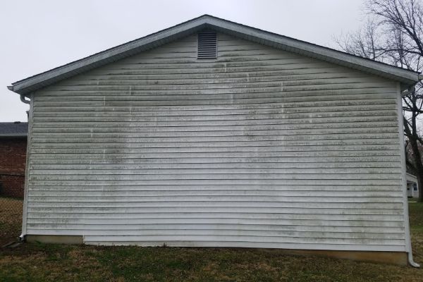 White house exterior with horizontal siding and a small gable vent under an overcast sky