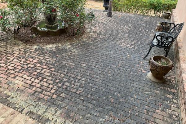Brick patio courtyard with potted plants and wrought-iron chairs along the wall