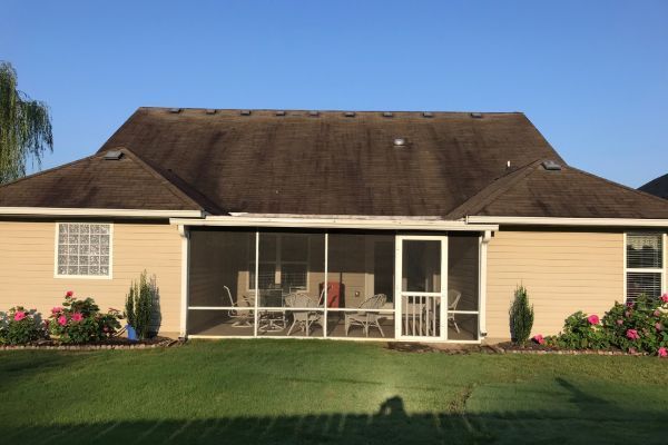Single-story beige house with a screened porch, dark brown roof, and a manicured front lawn