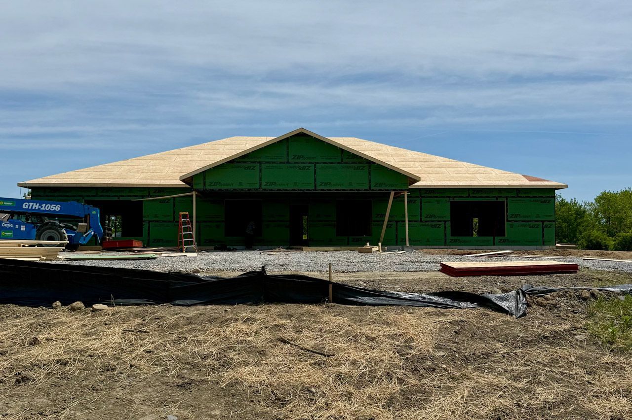 Green beach house under construction on a sandy shoreline under a blue sky
