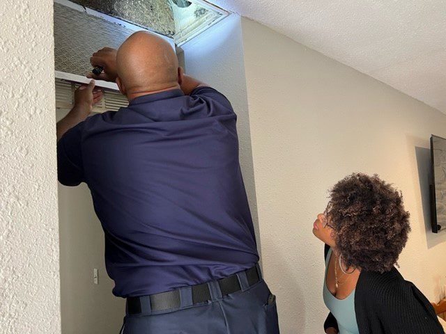 A man is working on a ceiling while a woman looks on.
