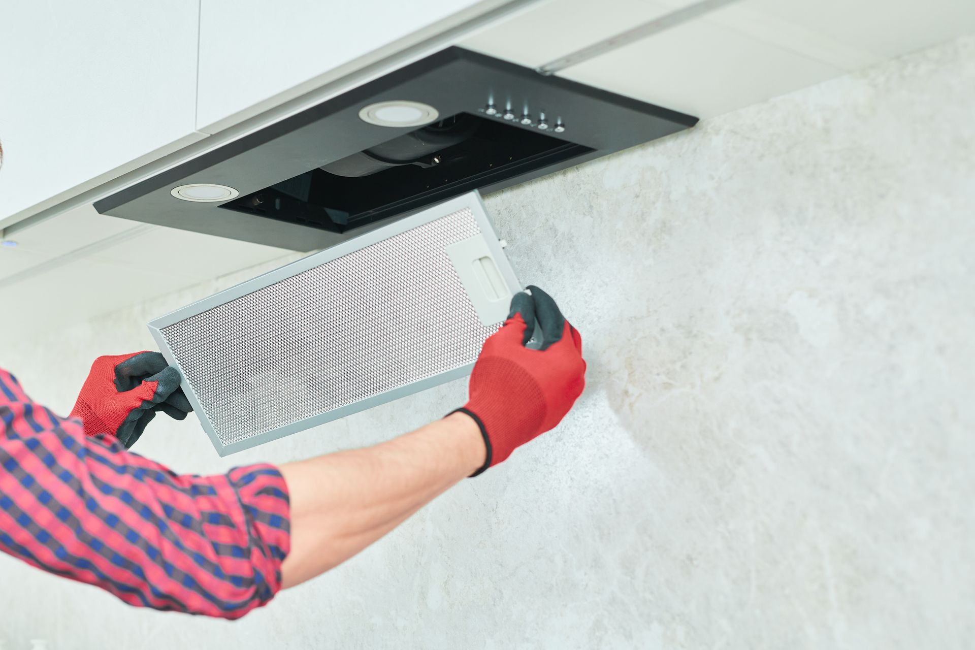 A person is cleaning a hood filter in a kitchen.