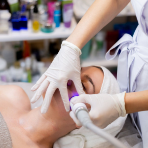 Gloved clinician using handheld device on a patient lying on a treatment bed in a spa clinic