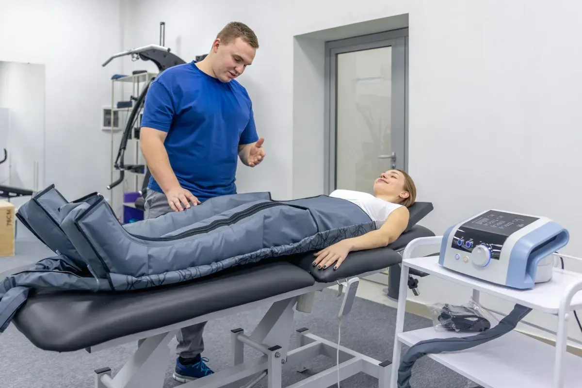 Therapy room with clinician adjusting a patient’s leg compression boots on a treatment table