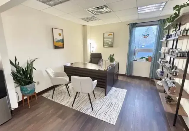 Bright modern office with desk, white chairs, plants, and shelves in a tidy room