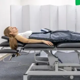 Person lying on a therapy table during a medical or physical therapy session, with straps on the torso.
