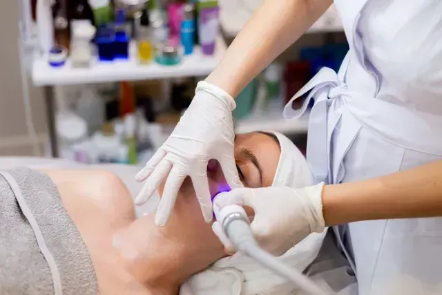 Aesthetic treatment with gloved technician using a handheld device on a client’s face in a clinic