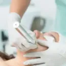 Dental cleaning in progress, with gloved hands using a tool on a patient’s mouth.