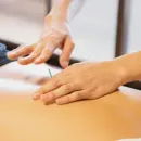 Hands massaging a person’s bare back on a treatment table