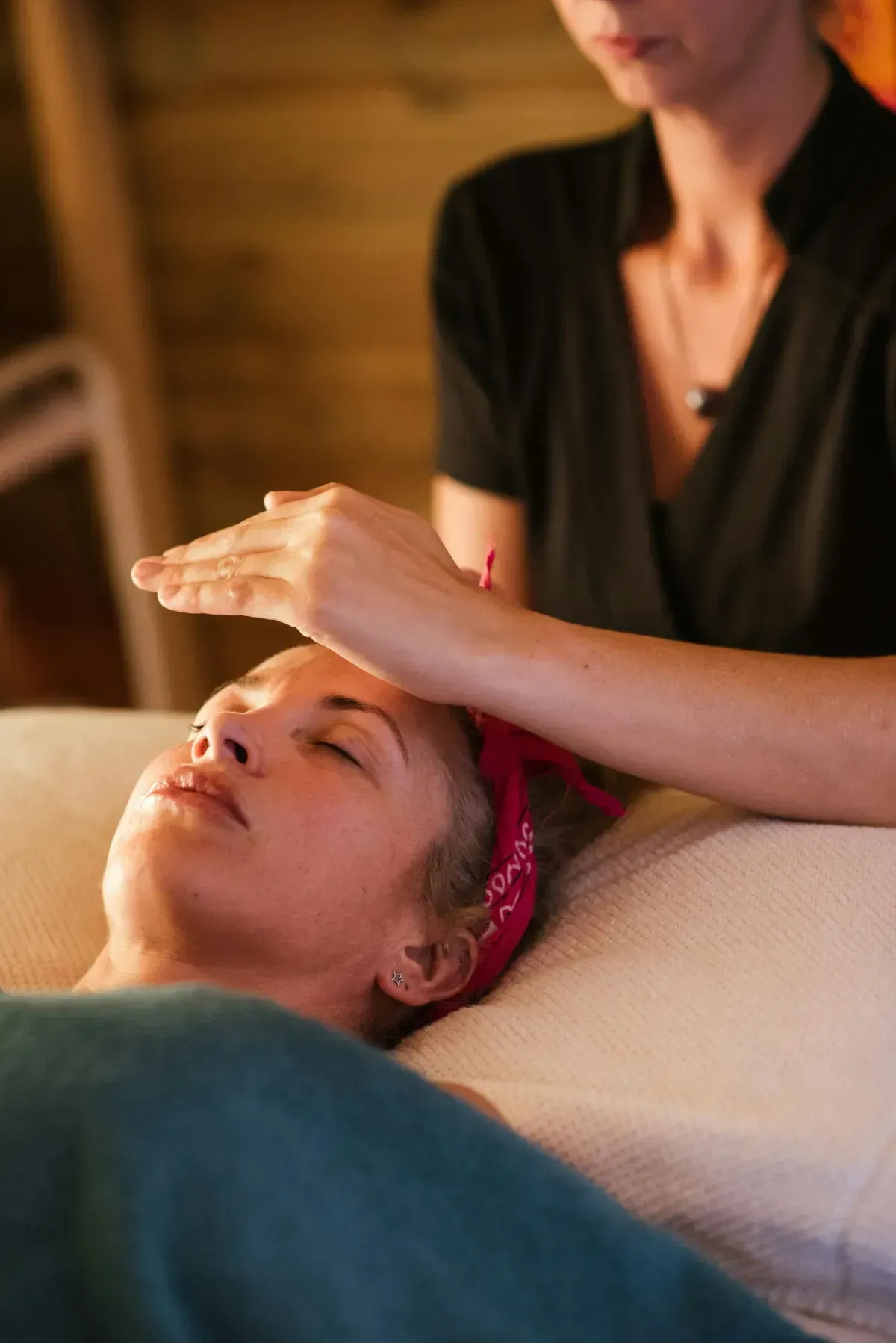 Spa therapist giving a facial massage to a reclining client in a warm, softly lit room