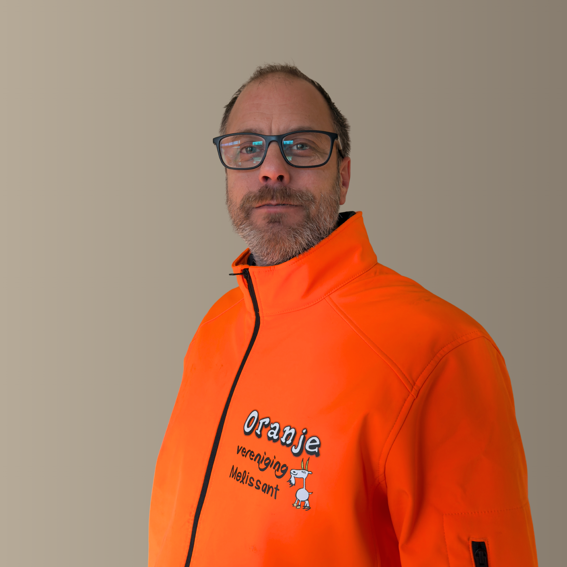 Een man met een bril en een oranje jas met tekst en een cartoongeit erop.