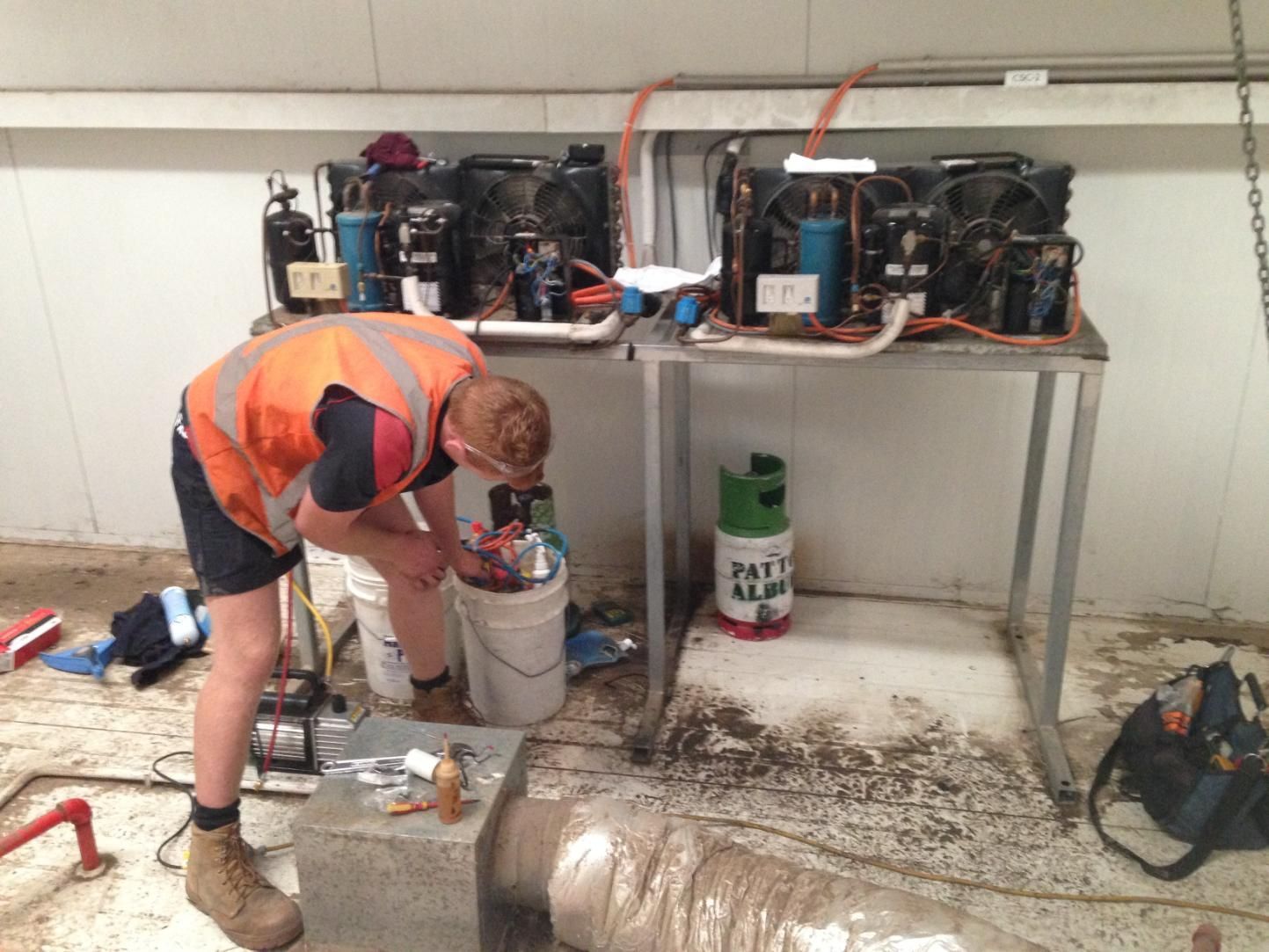A Man In An Orange Vest Is Working On An Air Condition — Custom Air In Mount Beauty, NSW