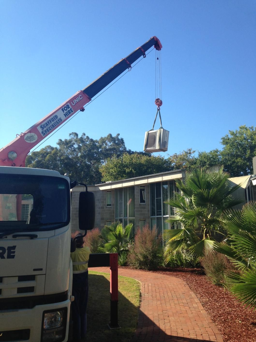 A Crane Is Lifting An Air Condition To The Roof — Custom Air In Wodonga, NSW