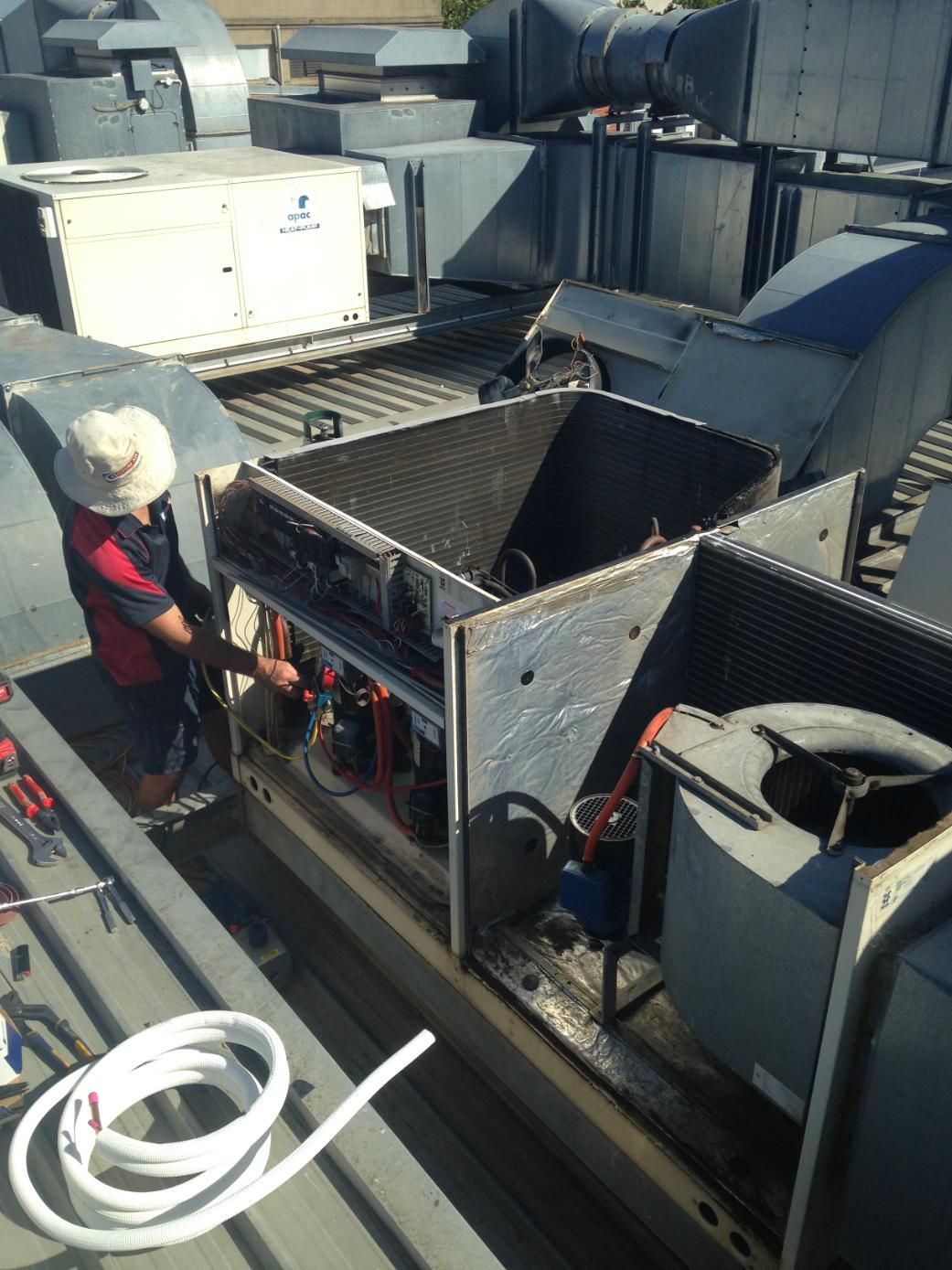 A Man Is Working On An Air Condition On The Roof Of A Building — Custom Air In Albury, NSW