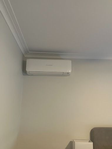 A White Air Conditioner Is Hanging From The Ceiling In A Living Room — Custom Air In Wodonga, NSW