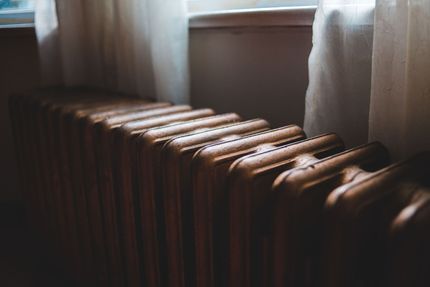 Vintage radiator below a window with sheer curtains in soft morning light