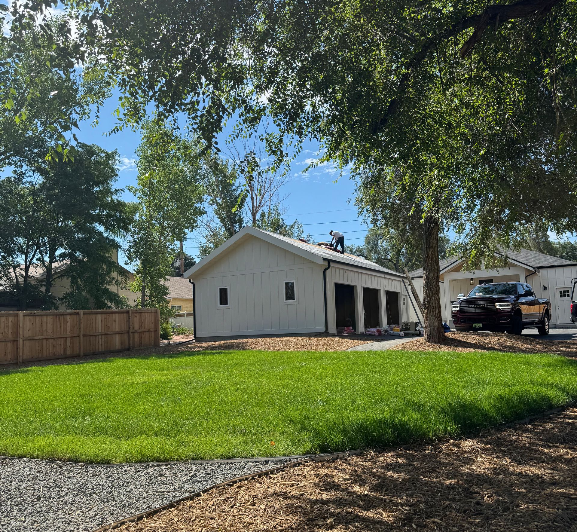 Single-story white house with a green lawn, trees, and a parked truck in the driveway.