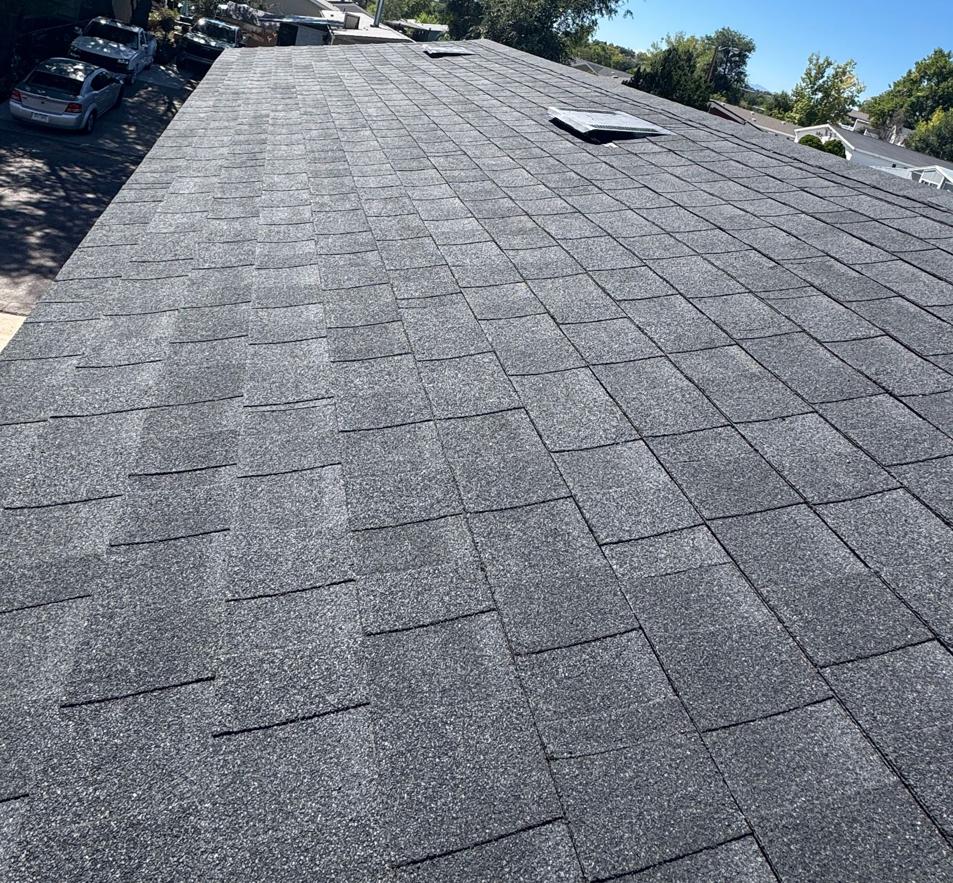 Gray shingle roof on a sunny day with a small rooftop vent visible near the top center