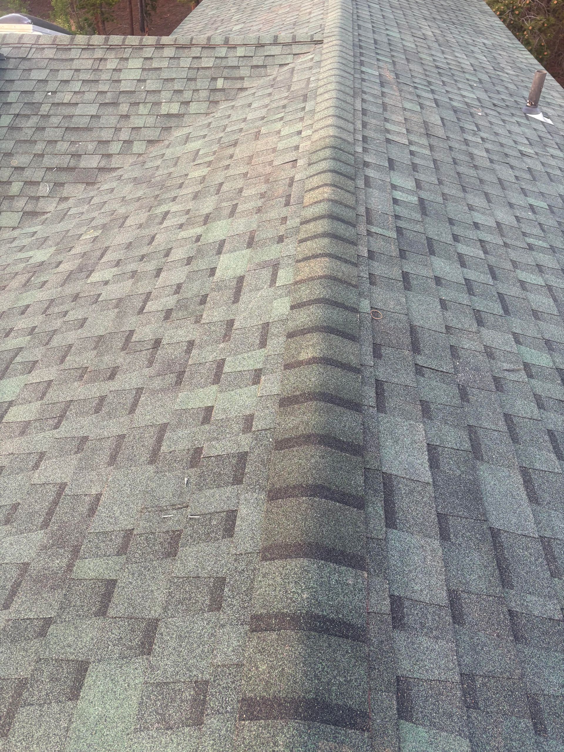Close-up of a gray shingled roof with a ridge line running down the center.