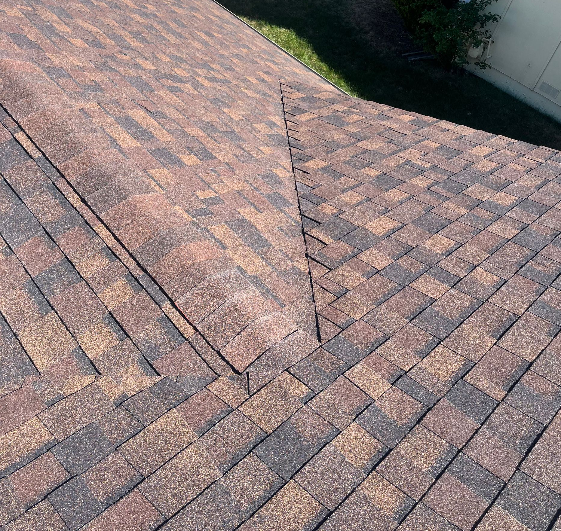 Close-up of a brown and gray shingled roof with a central ridge and diagonal patterns