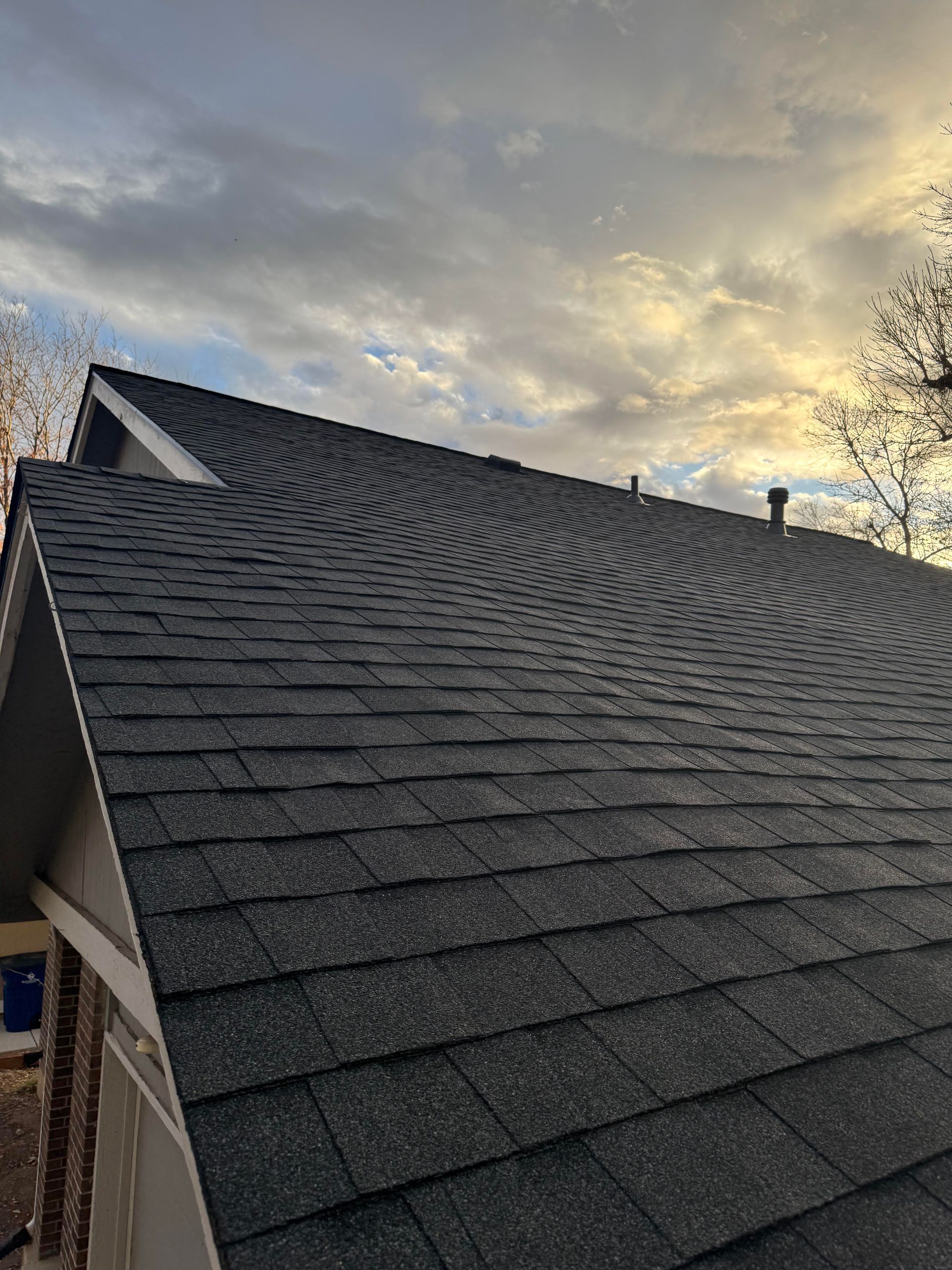 Dark gray shingled roof against a cloudy sunset sky