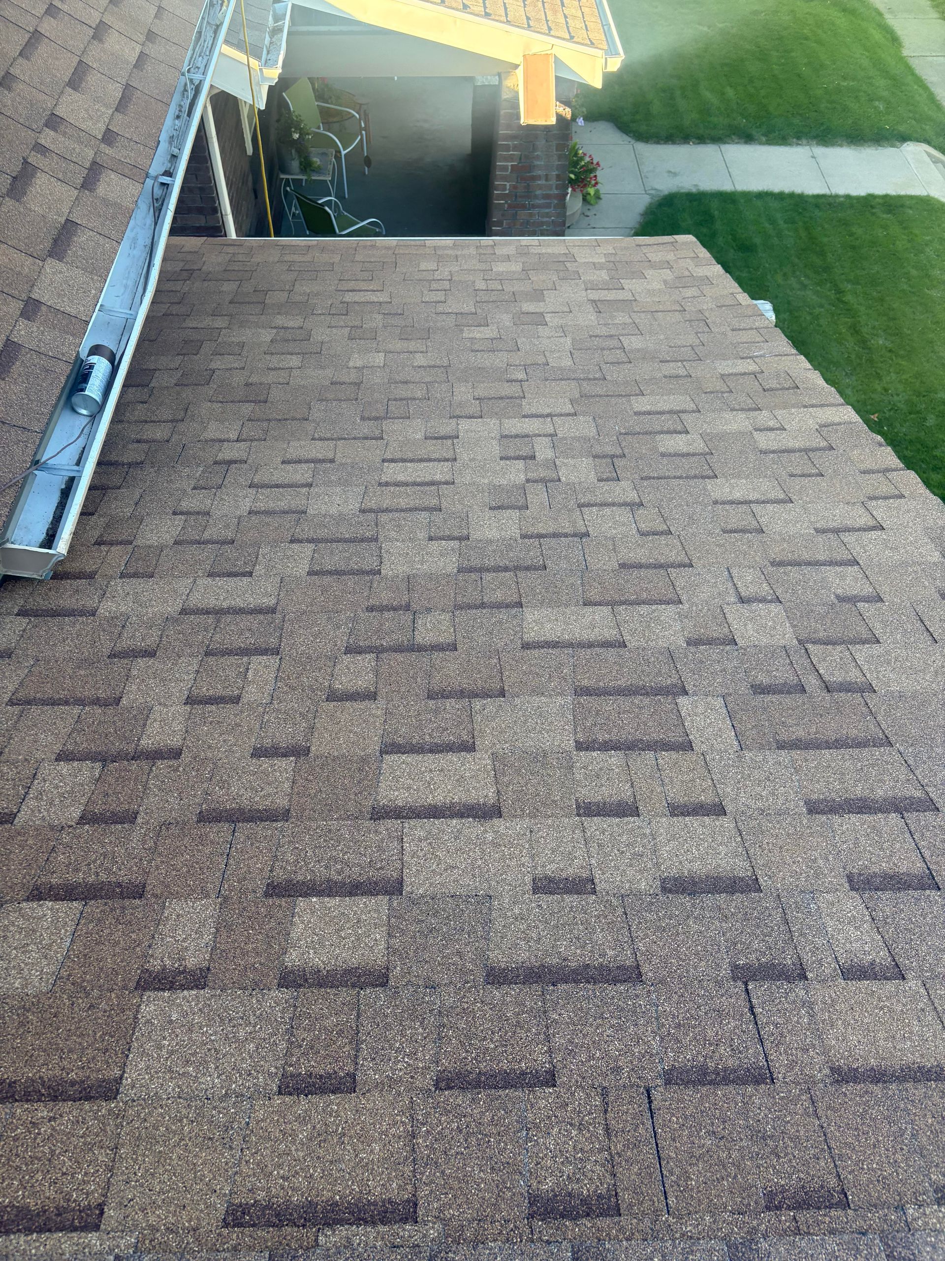 Rooftop shingle slope leading to a roof opening, with a ladder on the left and grass below.