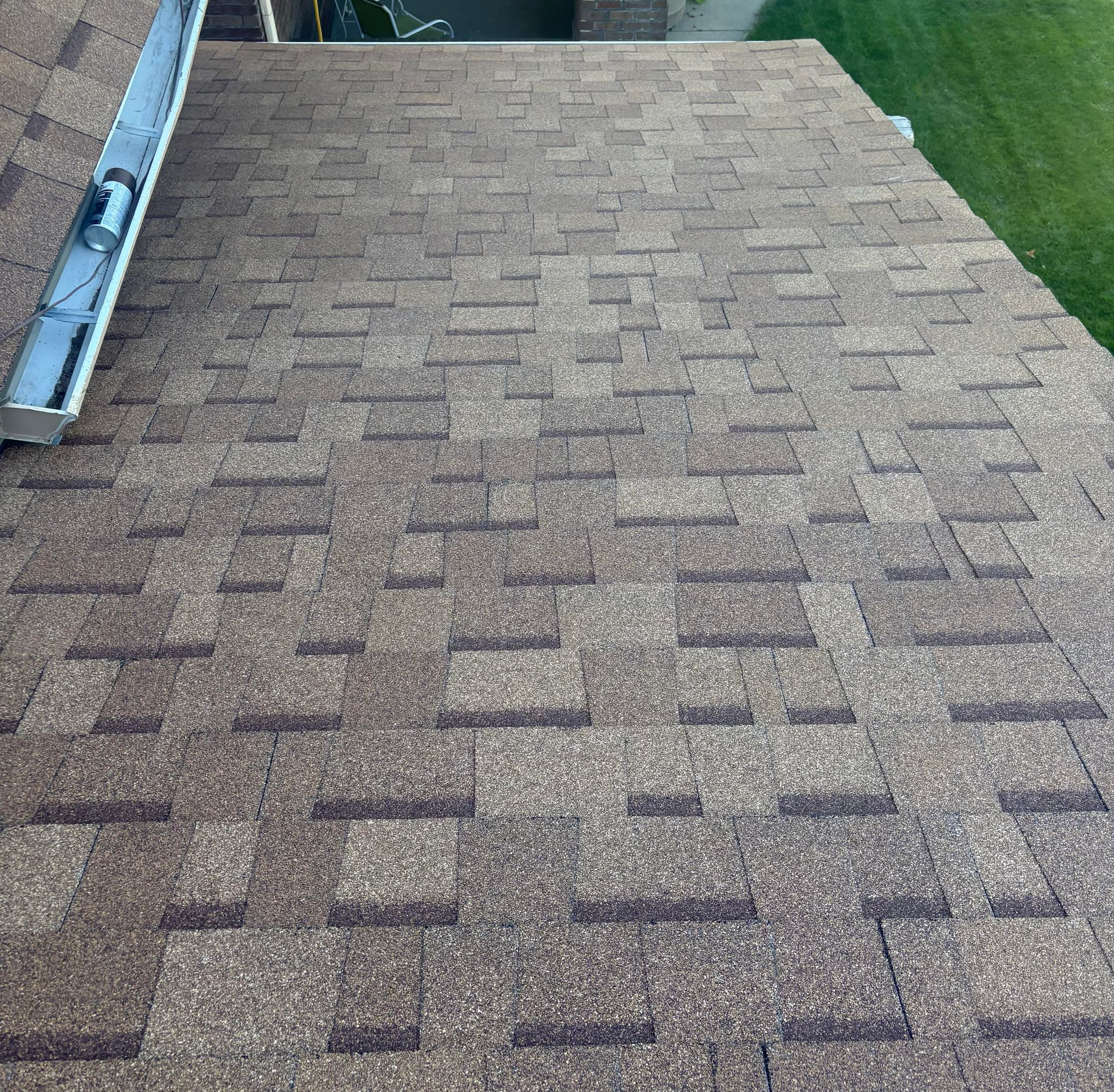 Shingled rooftop with brown-gray asphalt shingles and a gutter along the left edge