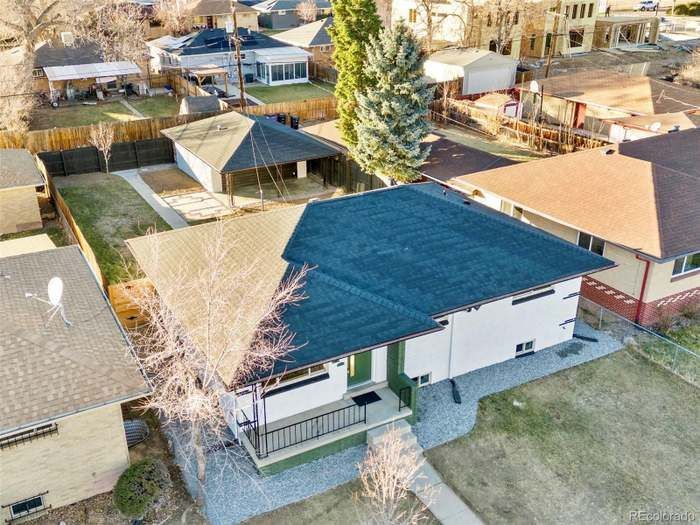Aerial view of a residential neighborhood with houses, yards, and a large evergreen tree