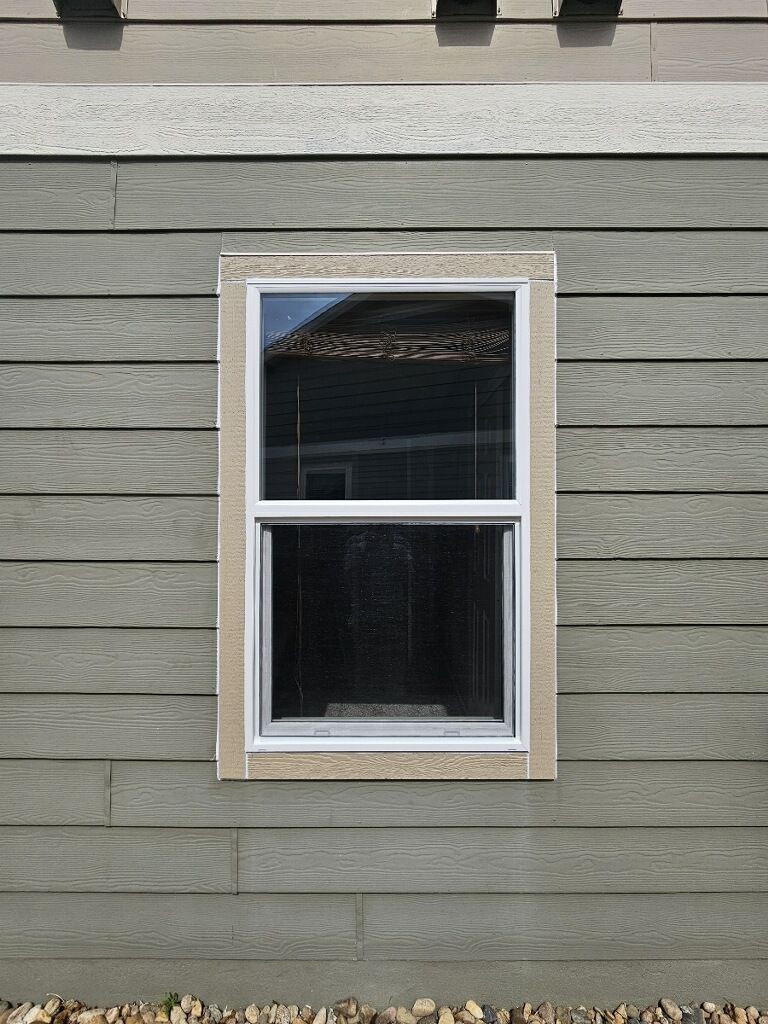 Single window with white trim on a gray siding exterior wall.