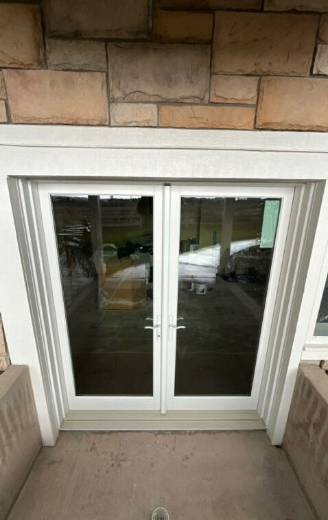 White double glass patio doors under a stone facade on a covered porch