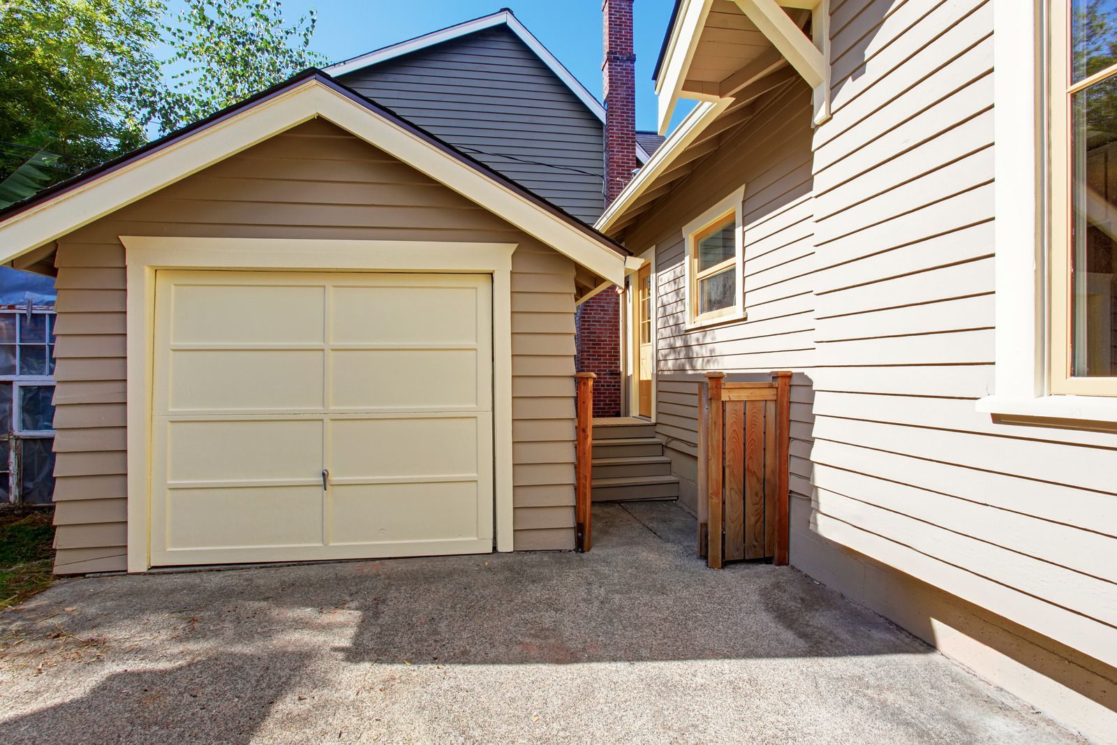 Narrow driveway beside a beige garage and house exterior under a blue sky