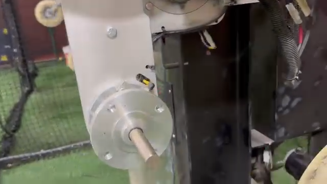 Close-up of a metal industrial machine with a cylindrical motor and attached tubing in a workshop setting