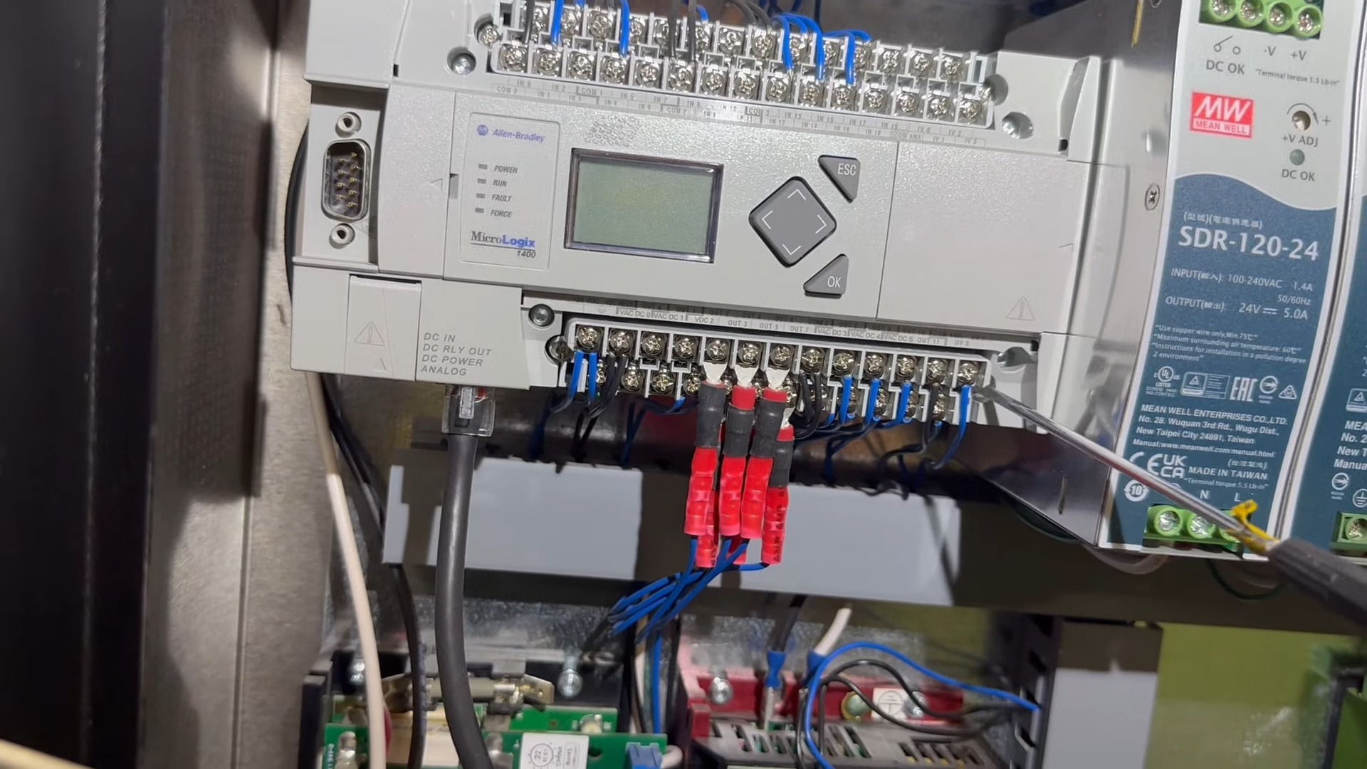 Close-up of an electrical control panel with a small display, buttons, wiring, and blue terminal blocks