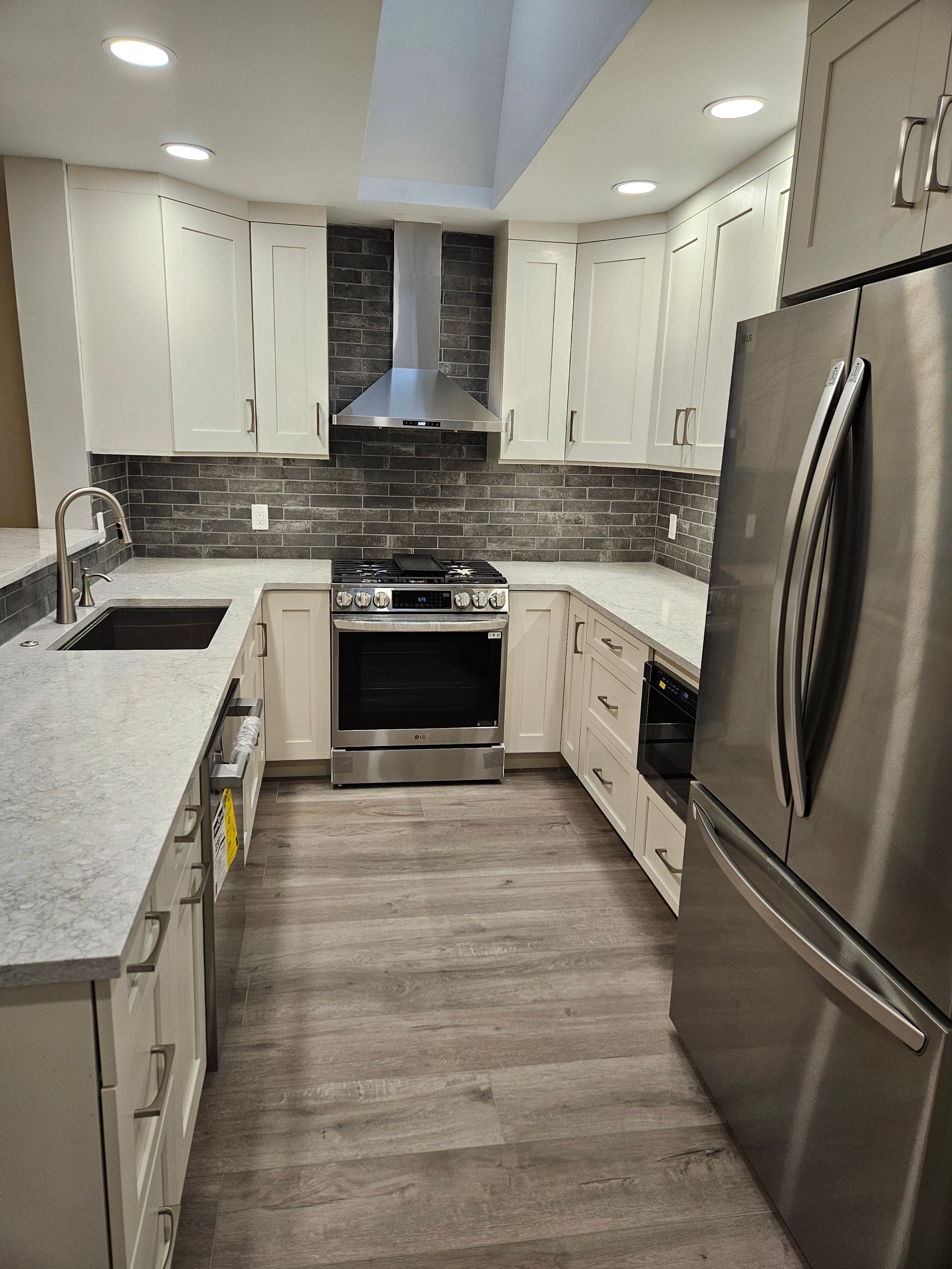 remodeled kitchen with white cabinets and stone backsplash