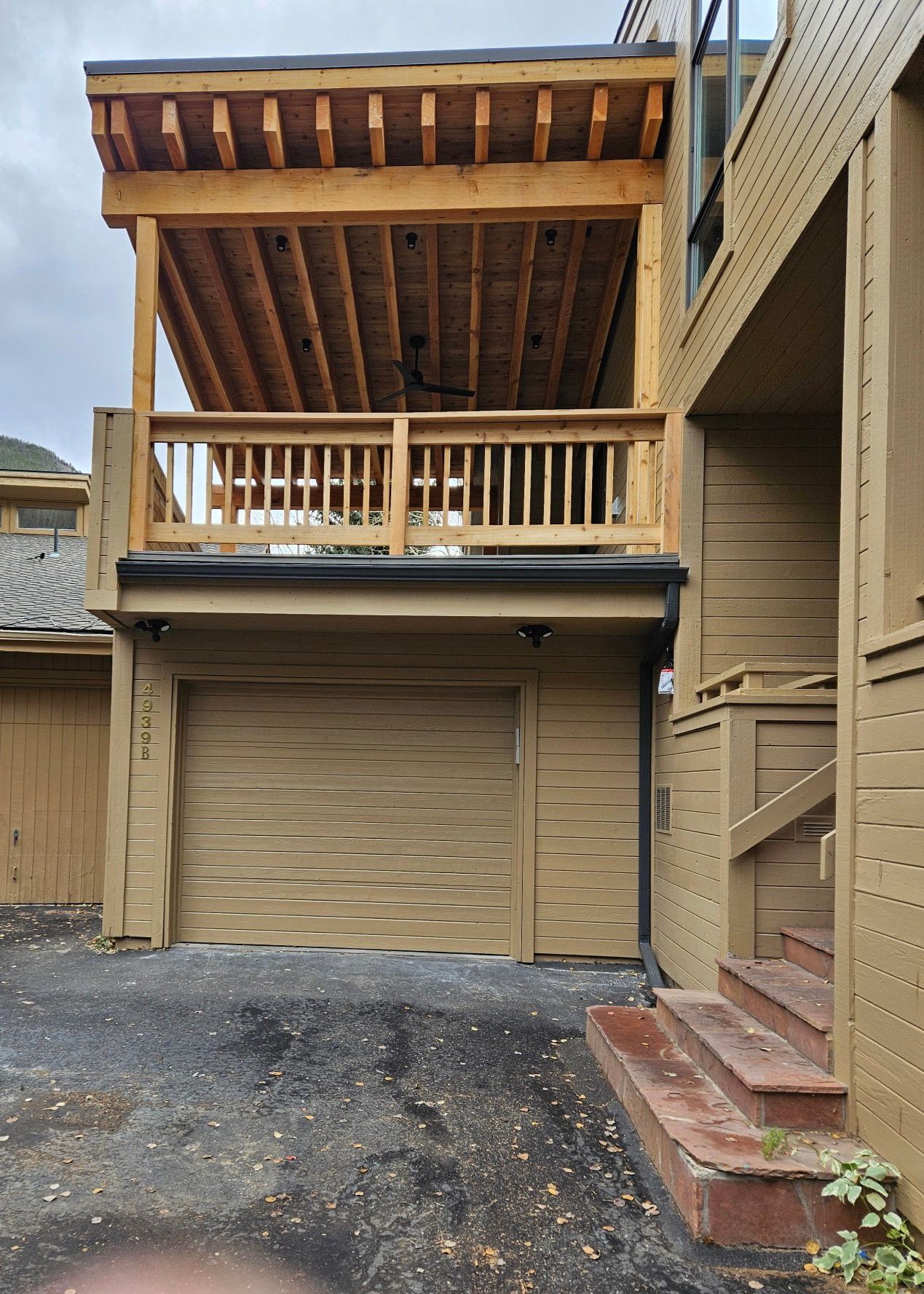 Second-floor wooden deck with railings attached to a house, overlooking the yard.