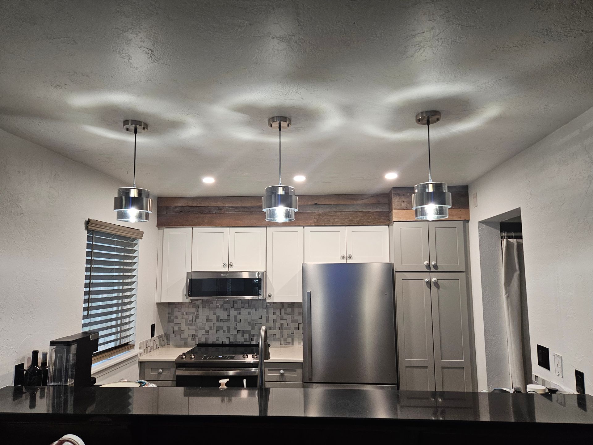 Modern kitchen renovation with white cabinets, stainless steel appliances, and pendant lighting over island.